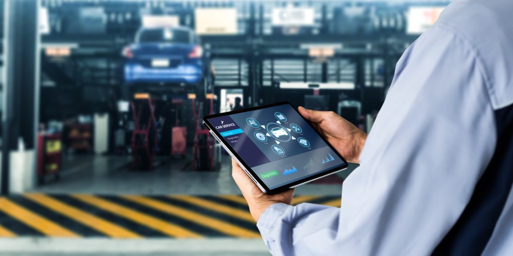 A technician using a tablet for car diagnostics.