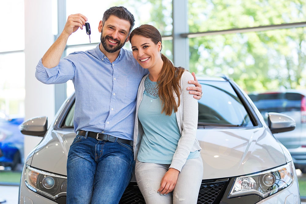 Couple holding up keys to new car